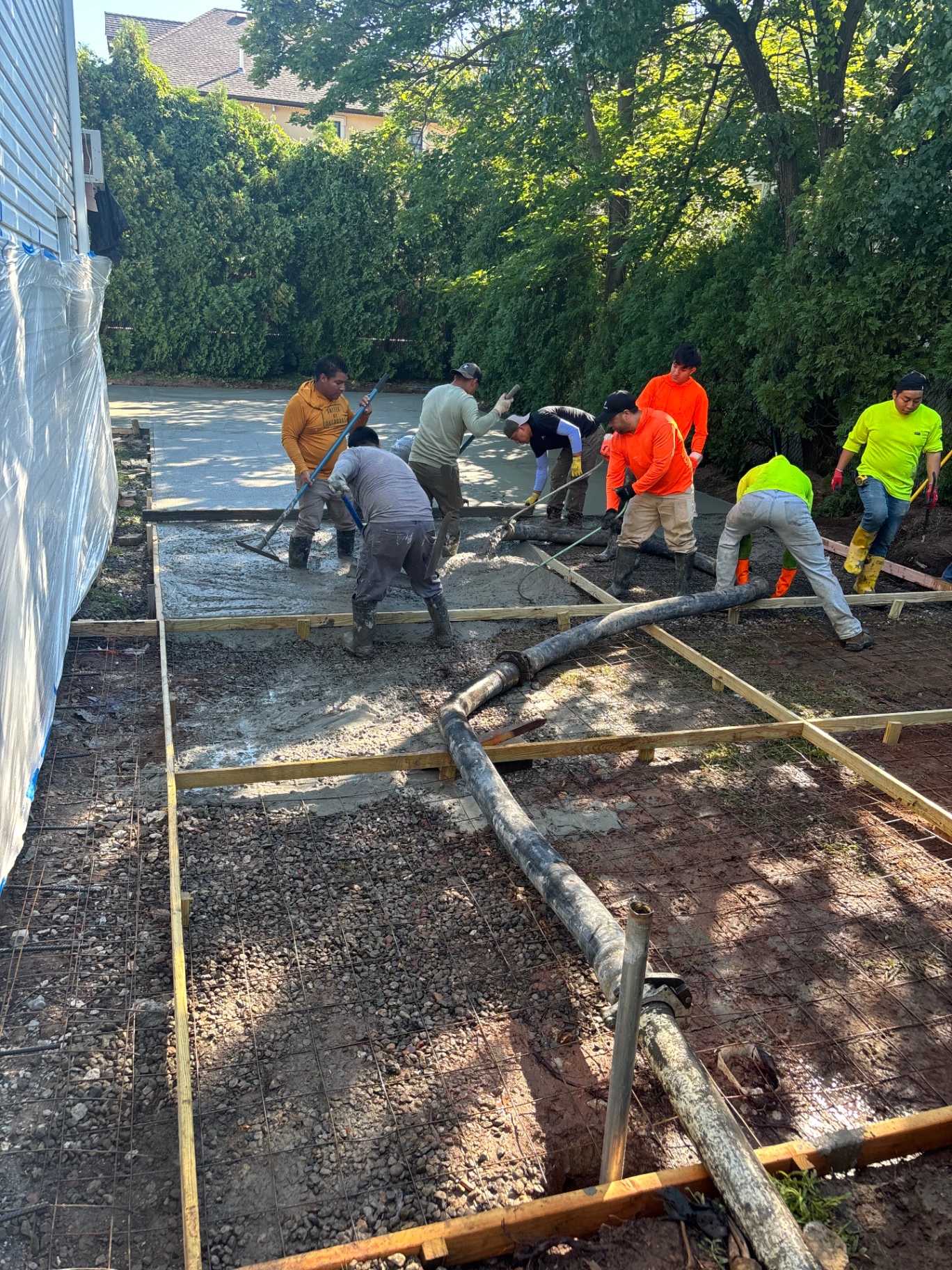 Crew pouring and screeding concrete over rebar mesh for a new Staten Island driveway