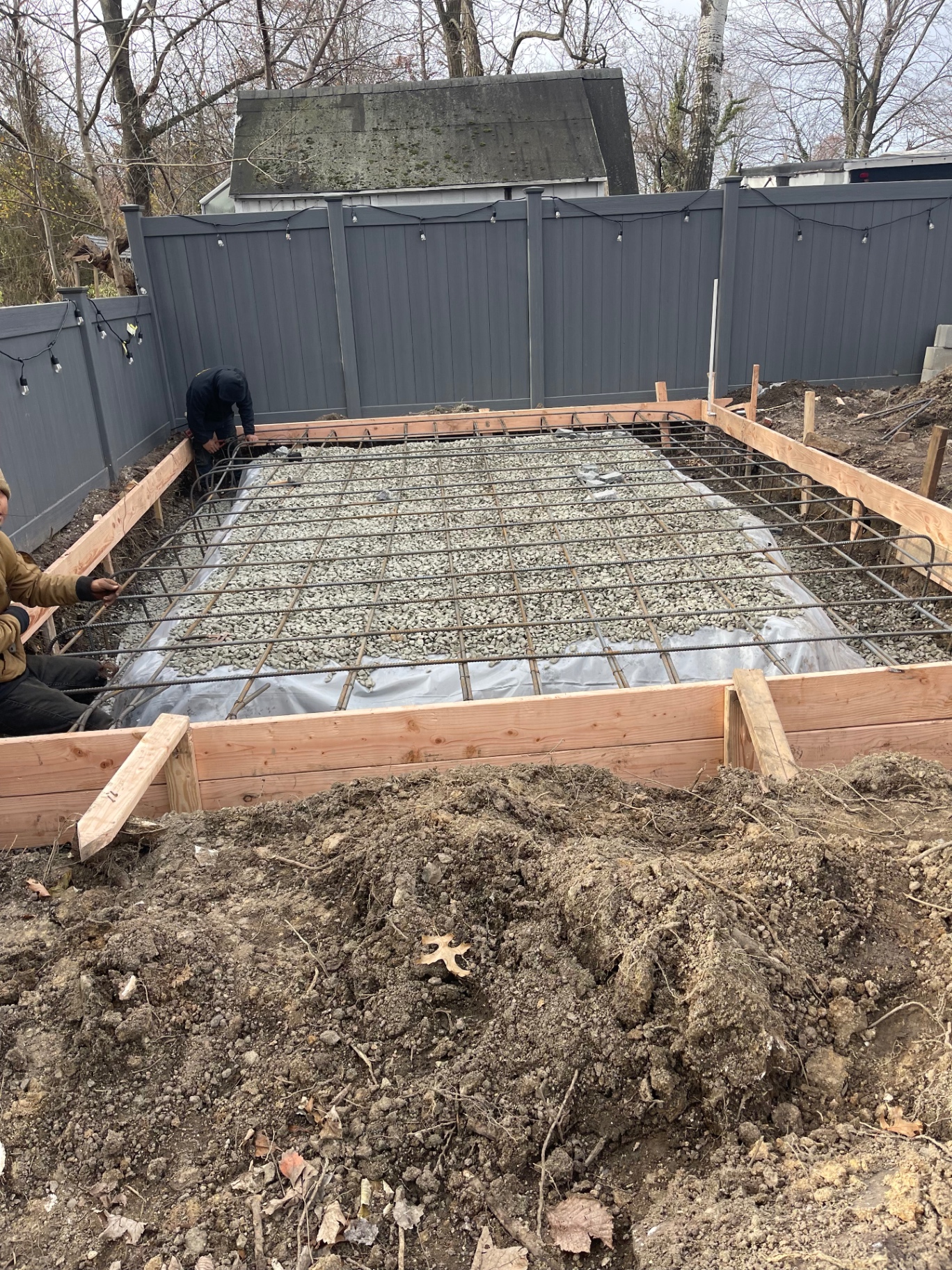 Concrete pad foundation formed with pressure-treated wood, rebar grid, vapor barrier and crushed stone base ready for pour