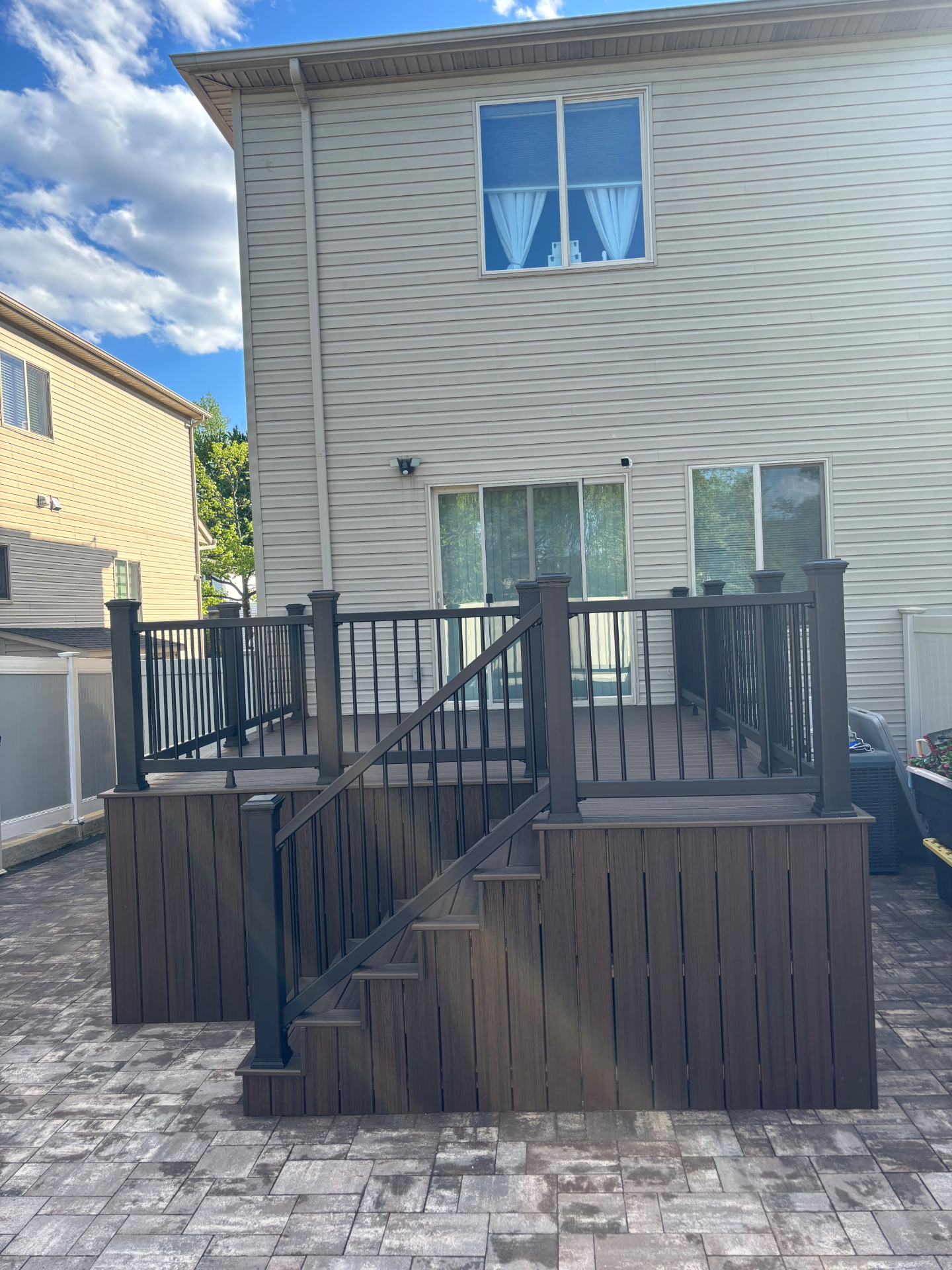 Finished raised composite deck with brown decking, matching skirting, and black aluminum railings