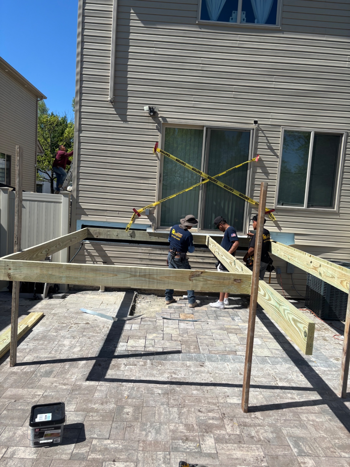 Crew installing the ledger board and starting the pressure-treated frame for the new raised deck