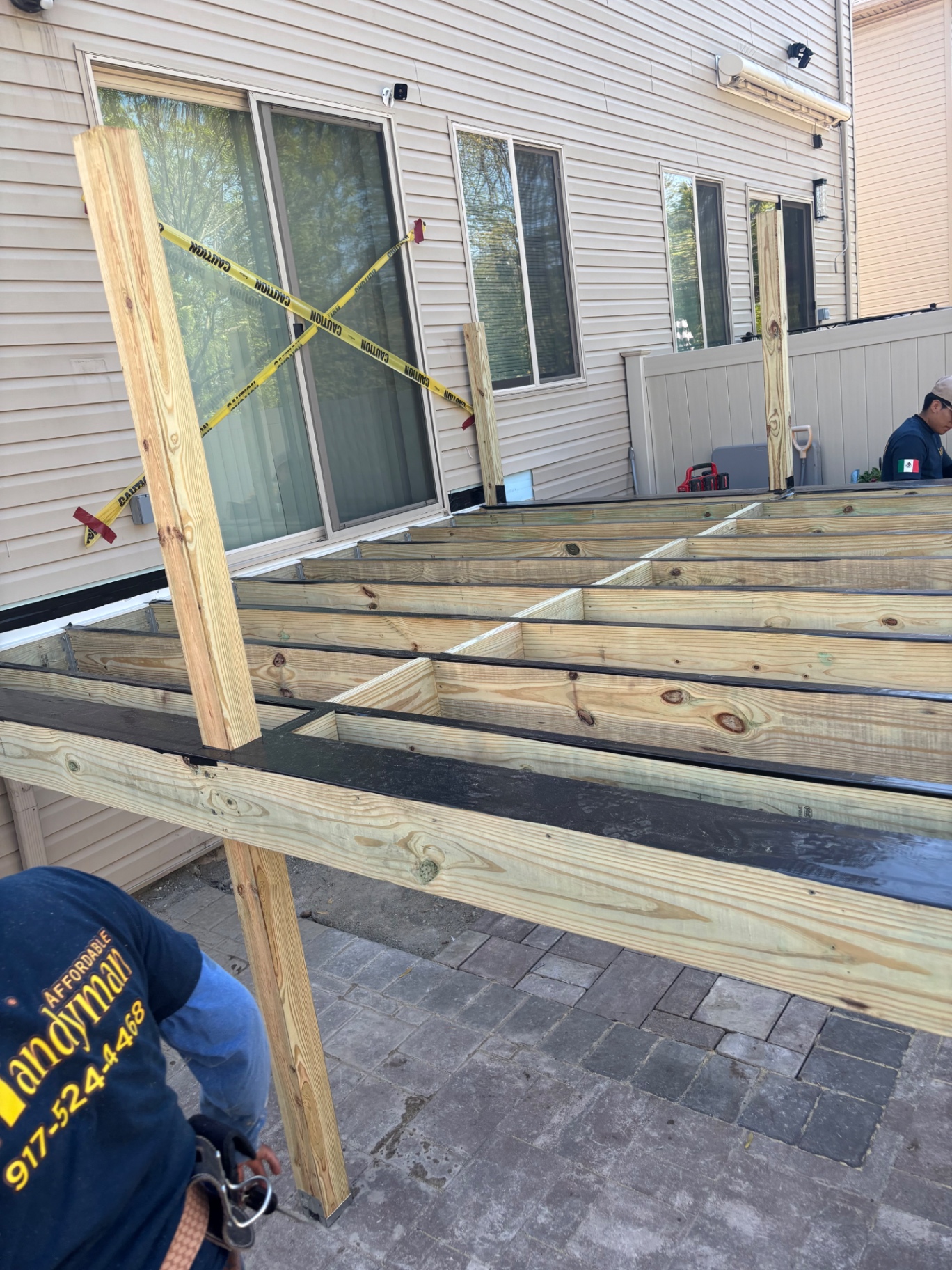 Pressure-treated joist framing and support posts for the new raised deck with flashing tape applied