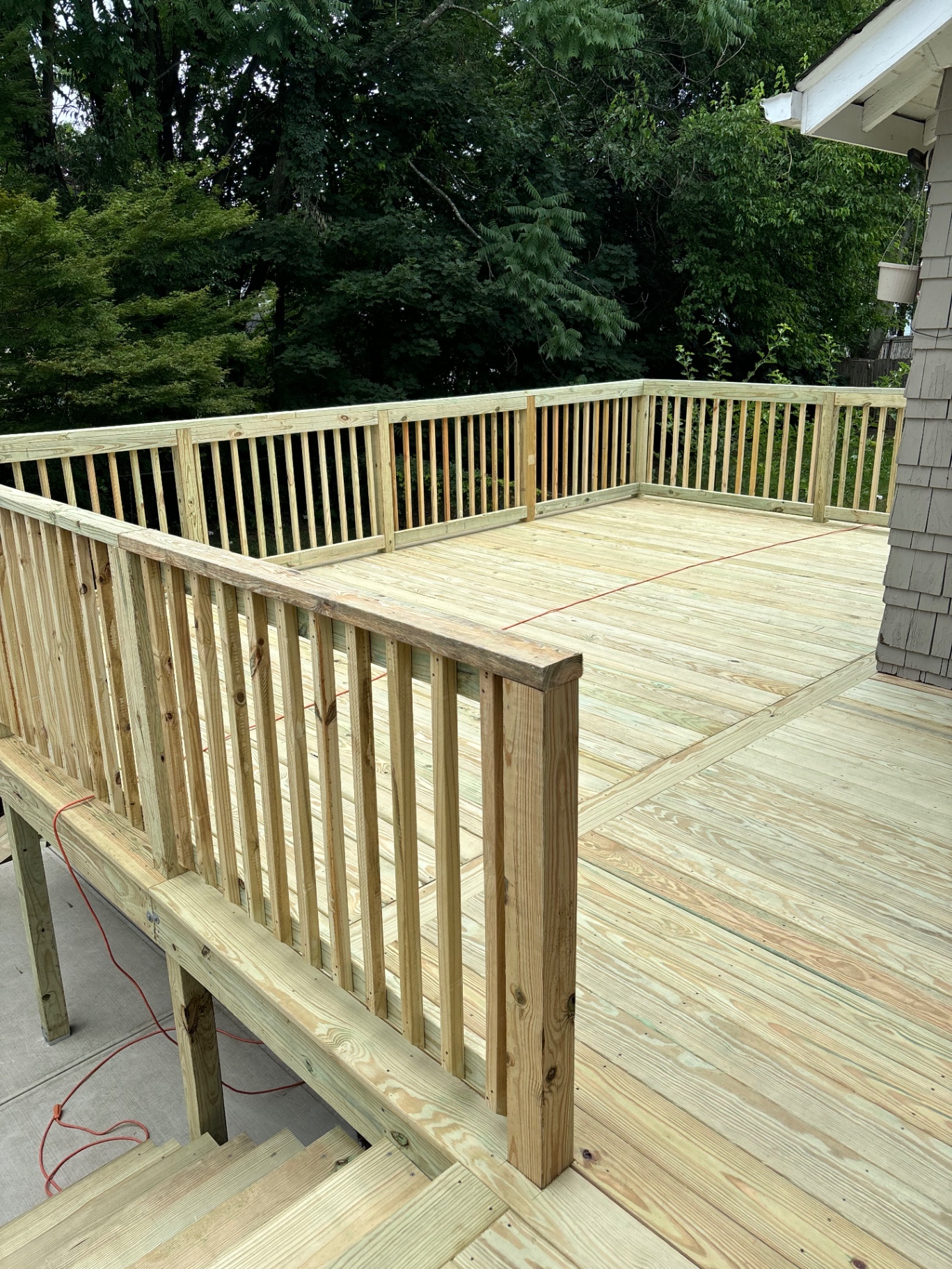 Finished elevated pressure-treated deck with custom railings, vertical balusters, and stair landing in backyard