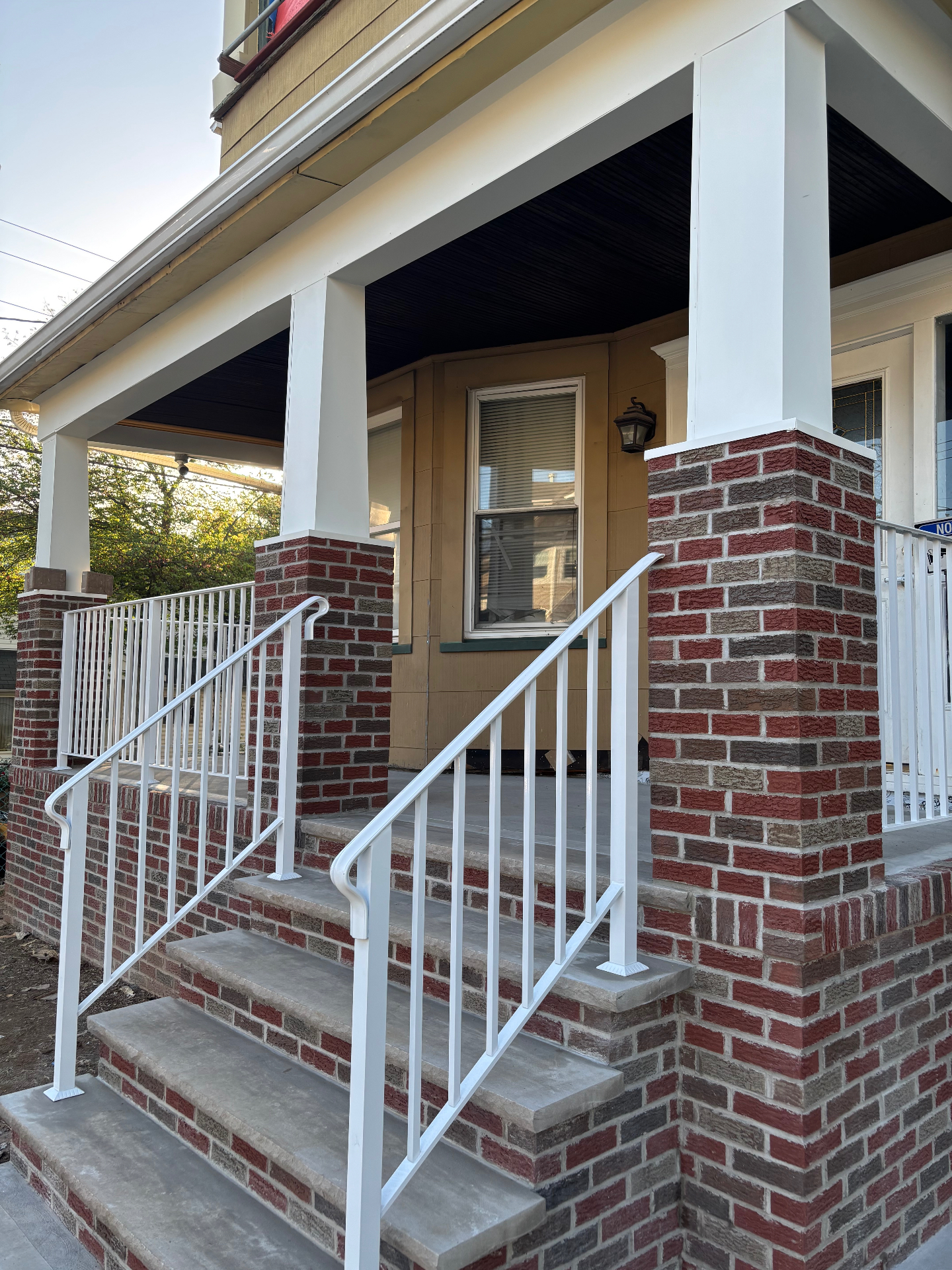 Close-up of finished brick column wraps, concrete steps, and white railings