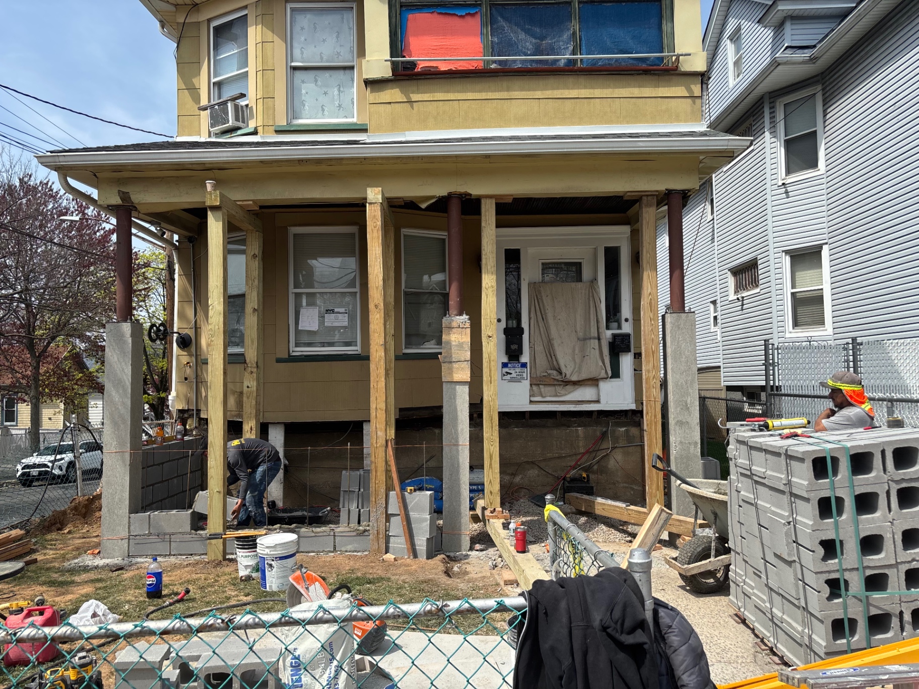Front porch before restoration with rotting wood posts and exposed framing during demo