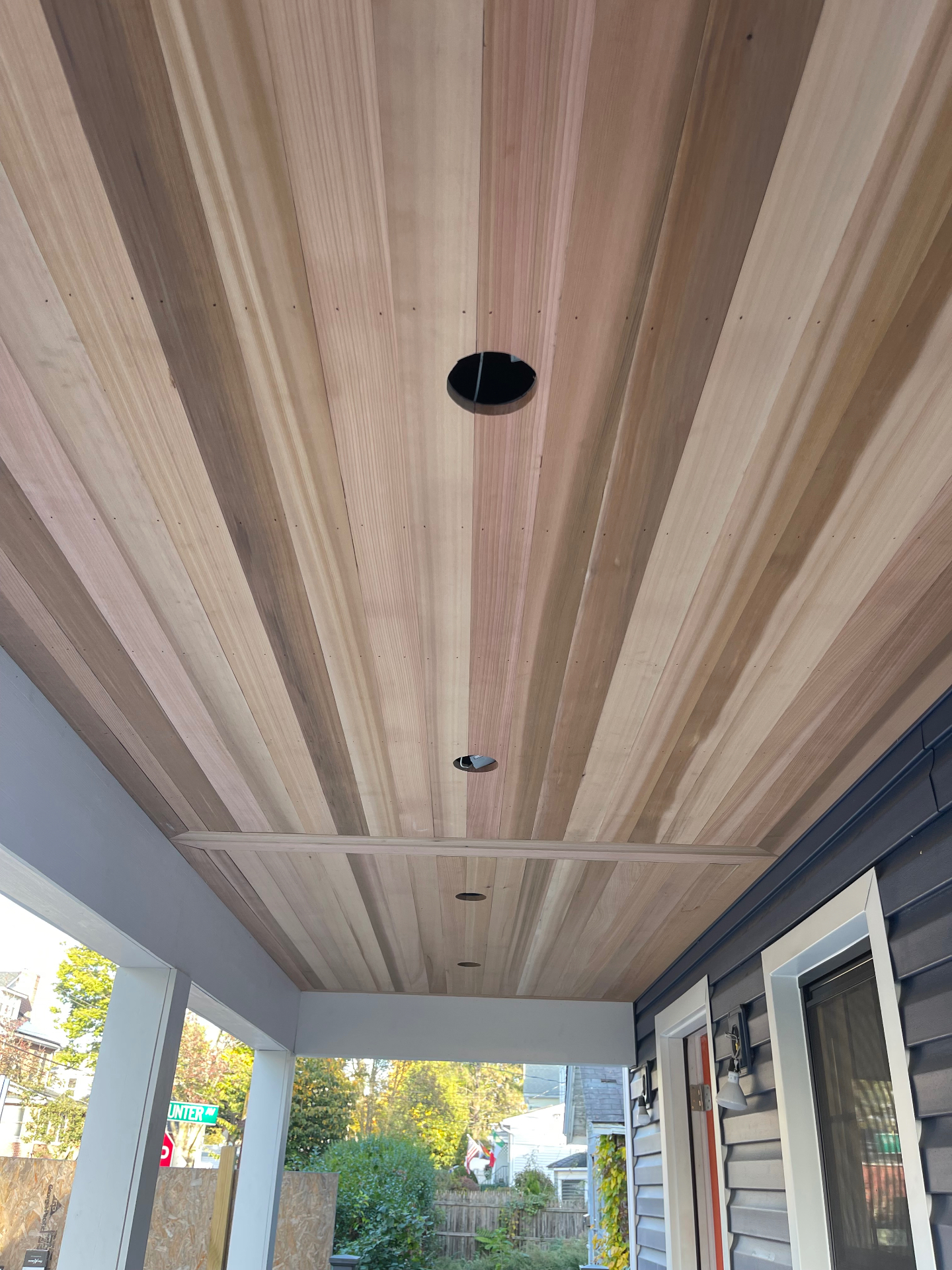 Tongue-and-groove wood-look porch ceiling with recessed light cutouts being installed