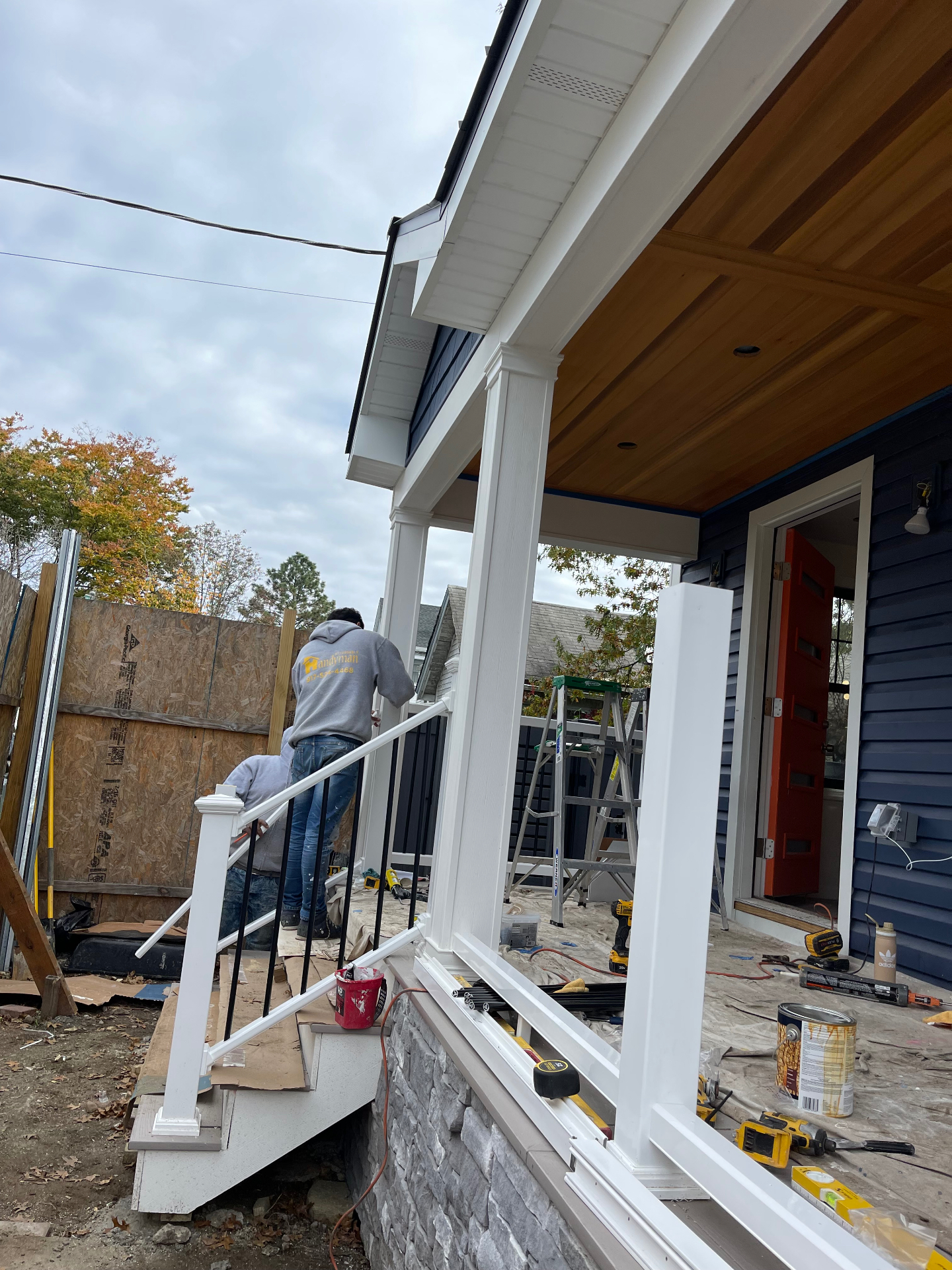 Porch railings and black balusters being installed on finished front porch