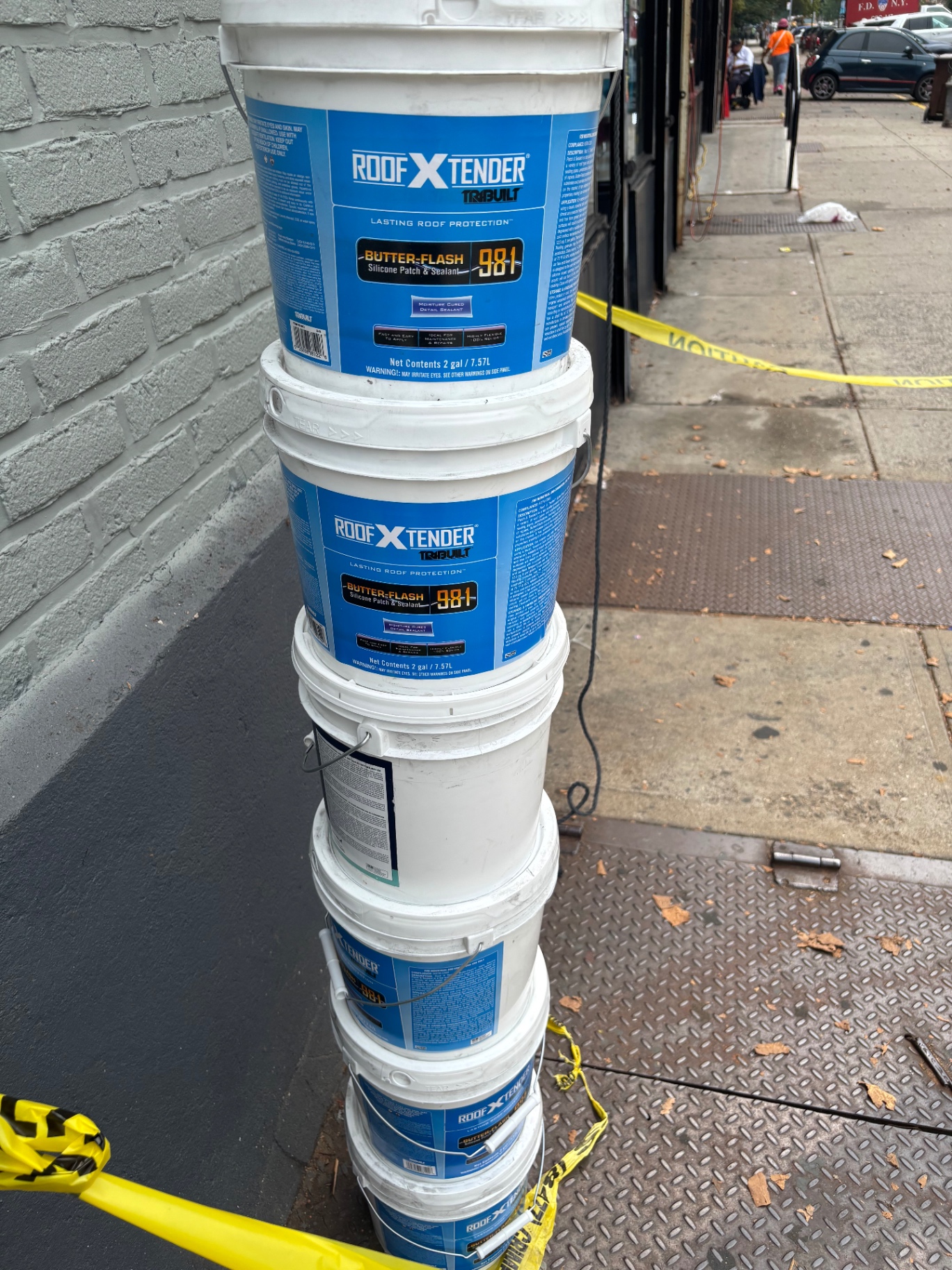 Stack of TRIBUILT Roof X-Tender Butter-Flash 981 silicone patch and sealant buckets used for the roof restoration